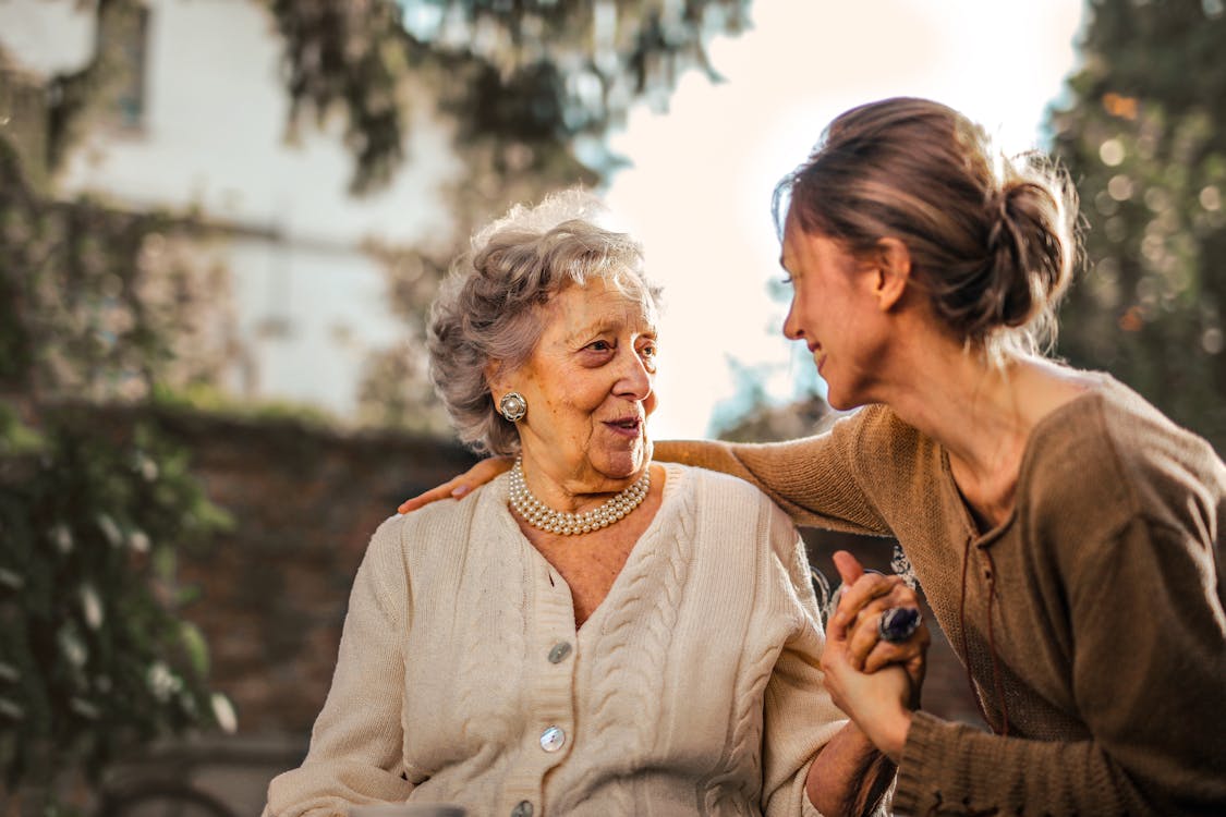 Two women are in a garden smiling as they speak to each other