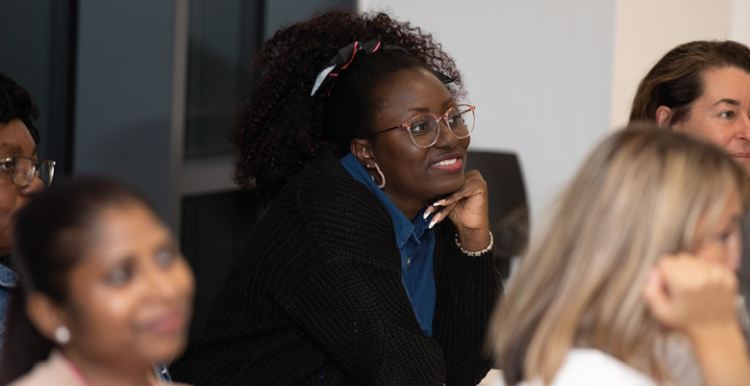People smiling while watching someone present at an event