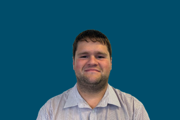 Photo of employee Ben smiling to camera against a dark blue background
