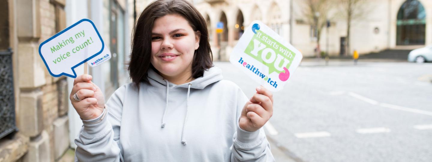 Young woman holding Healthwatch leaflets